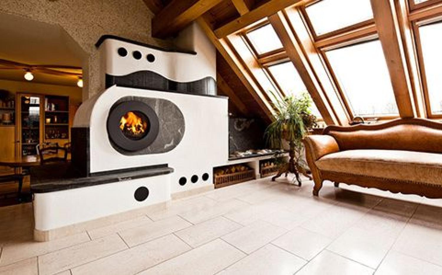 Firetube Ofen mit sichtbarem Feuer, integriert in wandähnliche Konstruktion mit mehreren Sitzflächen und Fächern für Holzscheite.