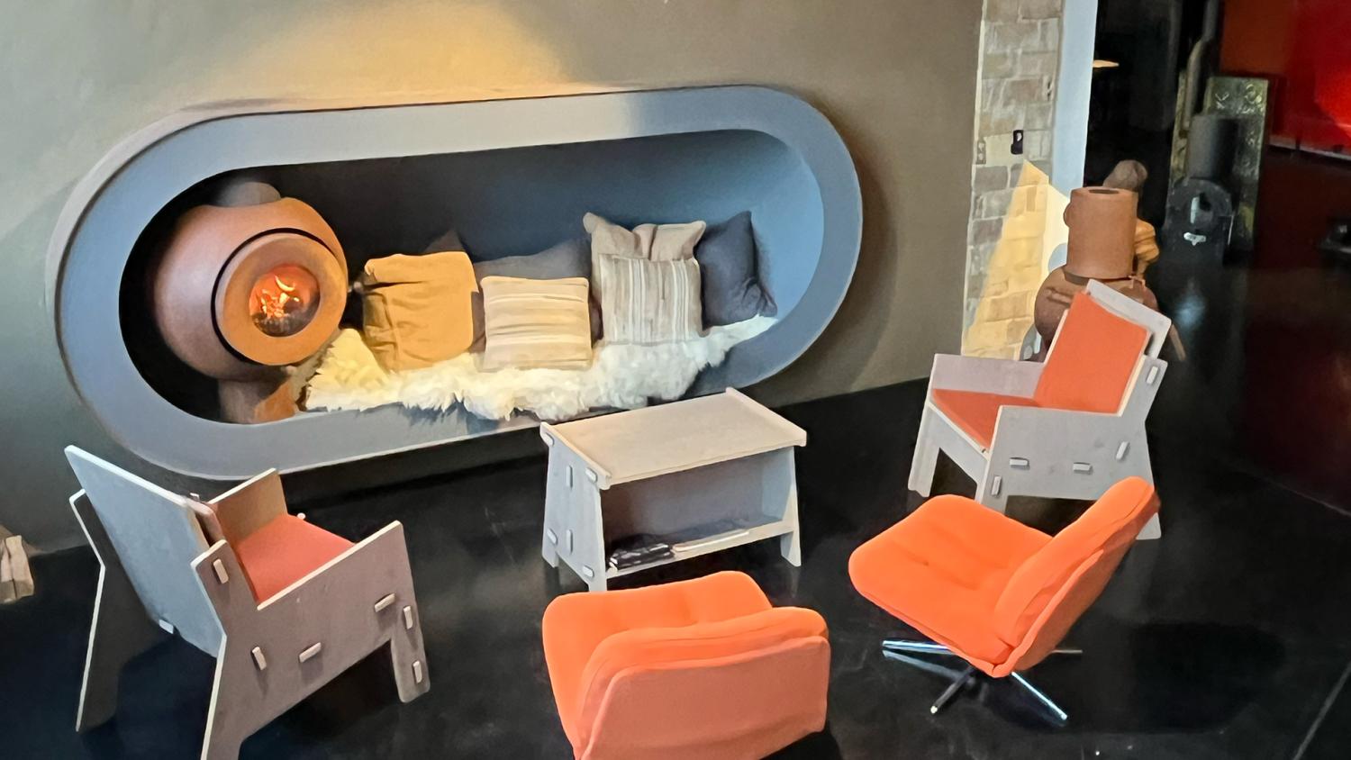 Firetube Ofen mit sichtbarem Feuer im rustikalen Look, in einer Sitzkuhle mit Kissen und Felldecke.