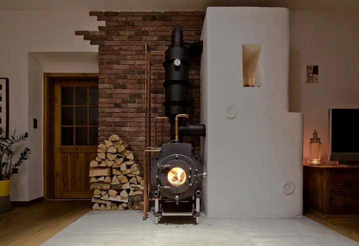 Zugeschnitten-Schwarzer firetube Ofen mit sichtbarem Feuer in wohnlicher Atmosphäre; links daneben gestapelte Holzscheite.