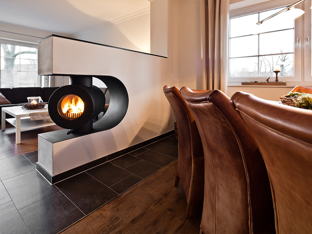 firetube Ofen mit sichtbarem Feuer, in eine trennende Wand zwischen Wohn- und Essbereich integriert.
