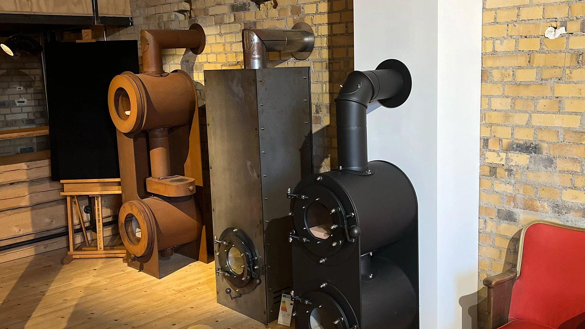 Drei firetube Öfen nebeneinander in unterschiedlichen Designs und Ausführungen, präsentiert in einer Ausstellung.